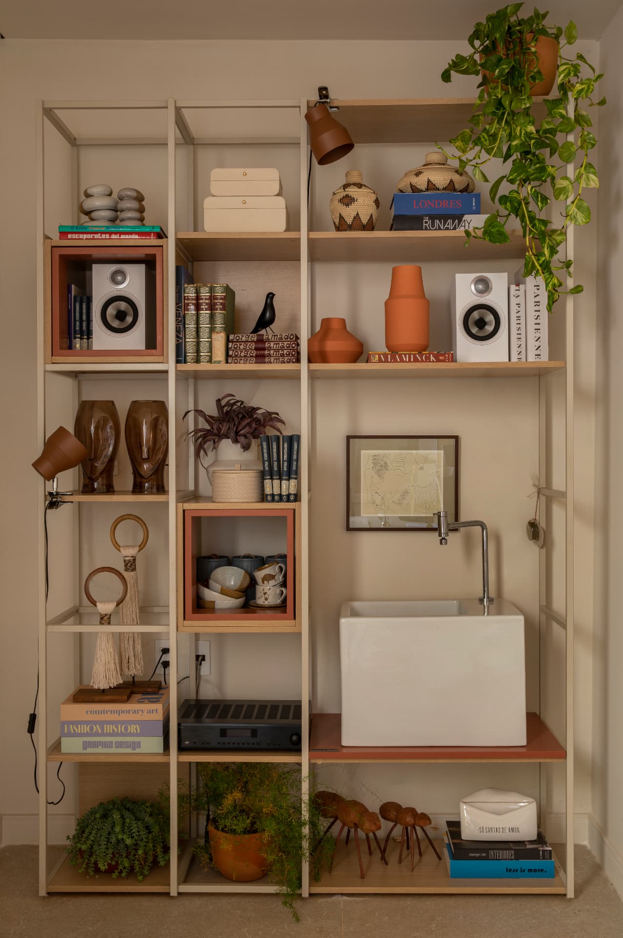 Estante integral com livros, cerâmicas, plantas e cuba branca