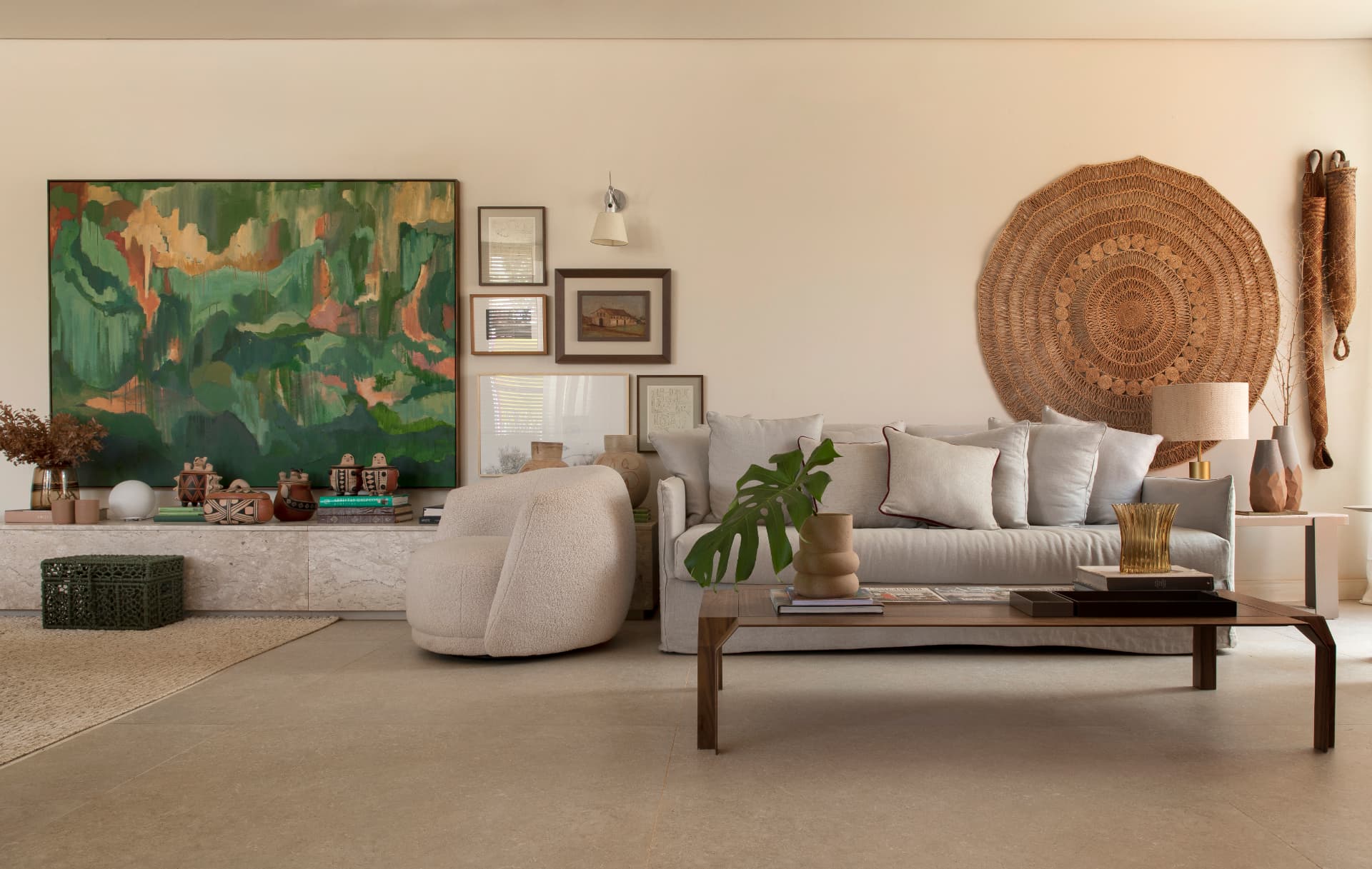 Sala de estar com sofá claro, painel de arte verde e peça circular em fibra natural