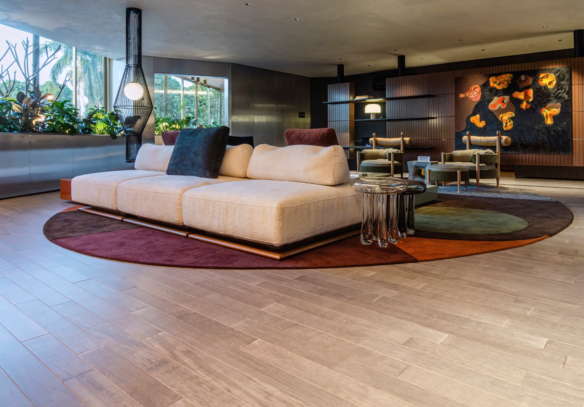Lounge com sofá modular claro sobre tapete redondo e arte na parede