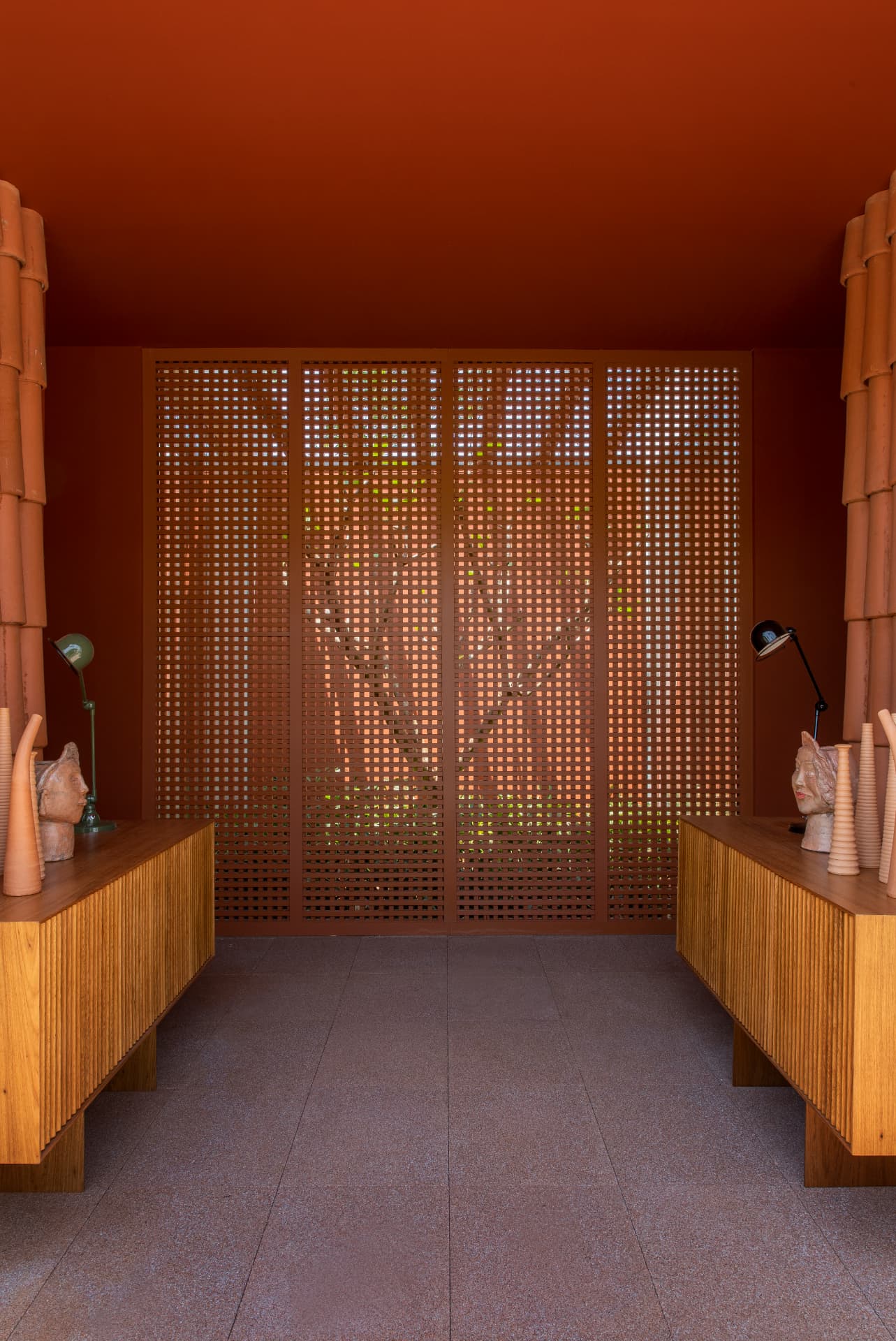 Ambiente simétrico em terracota com painel vazado e bufês ripados em madeira