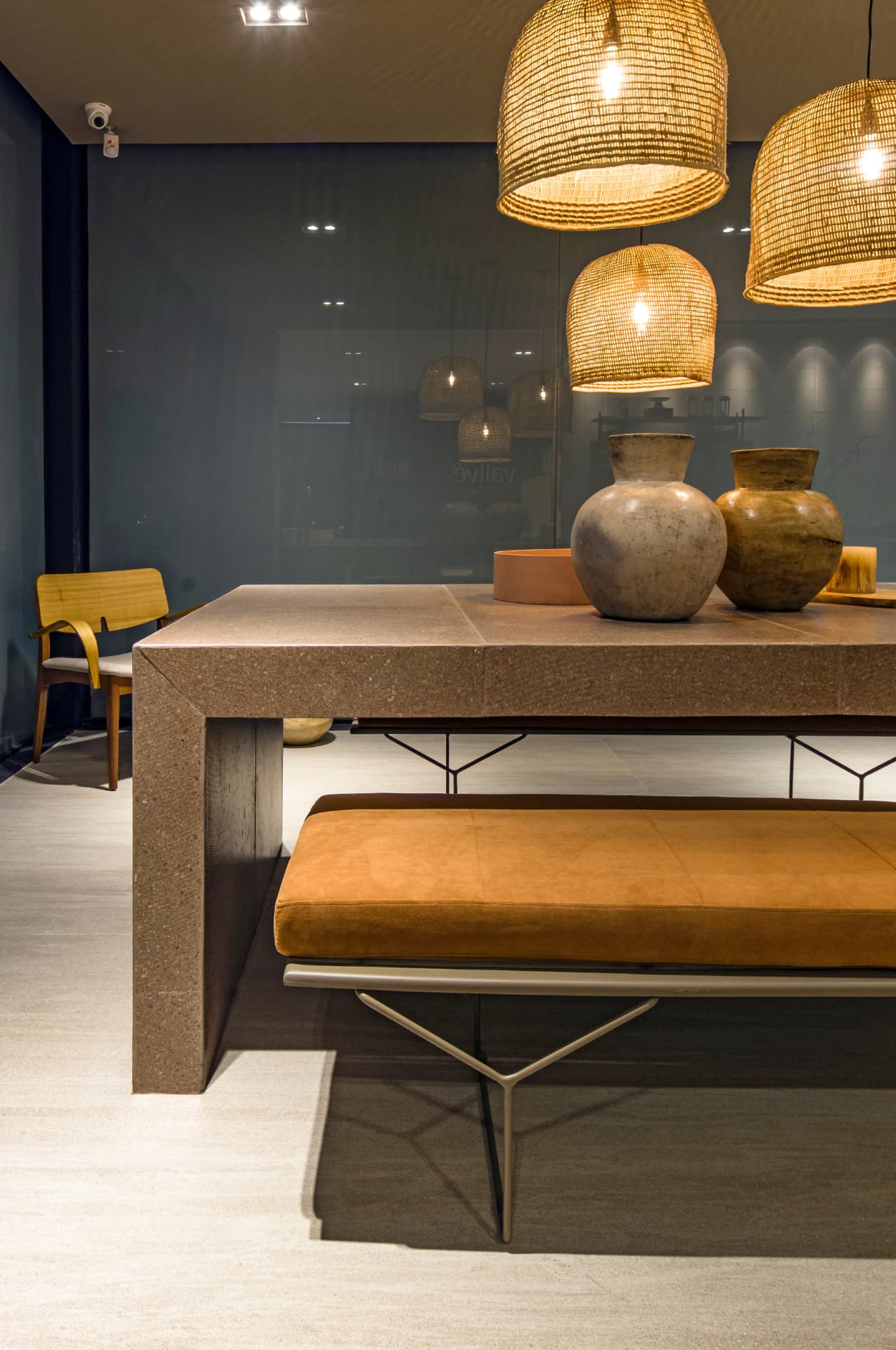 Showroom Casa Rara: sala de jantar com mesa em pedra, luminárias de fibra e vasos artesanais